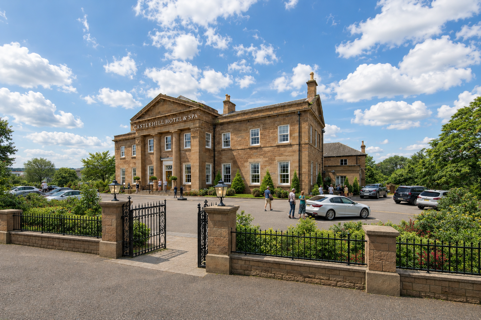 A large stone building labelled “Castlehill Hotel & Spa”, with people walking near the entrance and several cars parked in front, surrounded by greenery and a black metal fence under a partly cloudy sky.